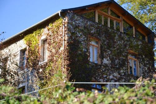 a building covered in ivy with windows and doors at Maison charmante à Gembrie + Piscine partagée & vue montagne in Gembrie