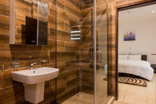 La salle de bains est pourvue d'un lavabo et d'une douche. dans l'établissement Accra Fine Suites - Holi Flats Airport Residential, à Accra