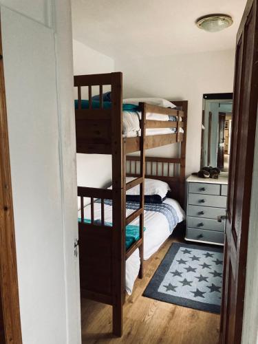 a bedroom with two bunk beds and a dresser at Eithin Bach in Caernarfon