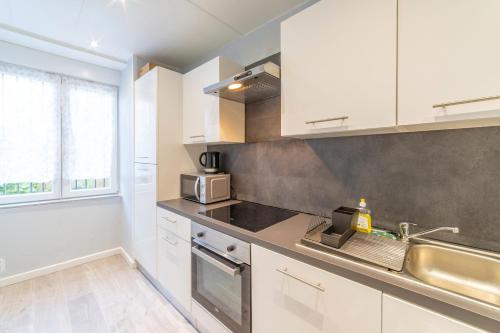 une cuisine avec des armoires blanches et un évier dans l'établissement ❂ LES ROCHES ❂ CHIC ❂ CENTRE ❂ 6 PERS. ❂ RDC ❂ RBNB ❂, à Mulhouse