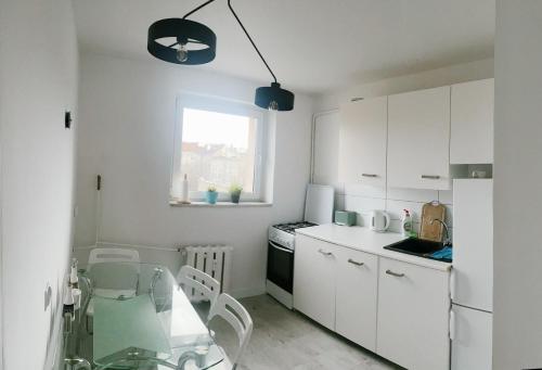 eine weiße Küche mit einem Glastisch und einem Fenster in der Unterkunft Stanisława Dubois 29, Wrocław in Breslau