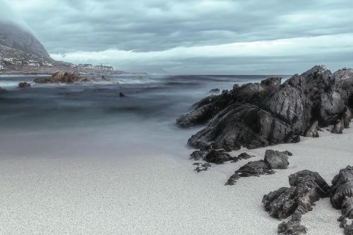 a beach with rocks and the ocean on a cloudy day at Aloe Ocean Flatlet in Bettyʼs Bay