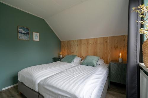 a bedroom with a bed with white sheets and green walls at Mosselbank 93 - Noordzeepark Ouddorp, with private front and back garden near the beach - not for companies in Ouddorp