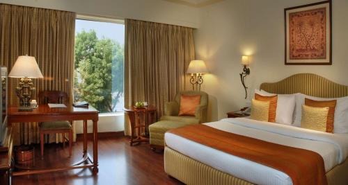 a hotel room with a bed and a desk and a window at Park Plaza Jodhpur in Jodhpur