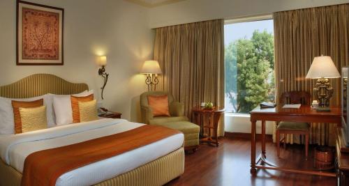a hotel room with a bed and a desk and a window at Park Plaza Jodhpur in Jodhpur
