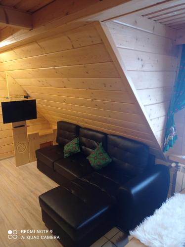 a living room with a leather couch and a flat screen tv at Pokoje ,,Goramiba''Jurgów in Jurgów