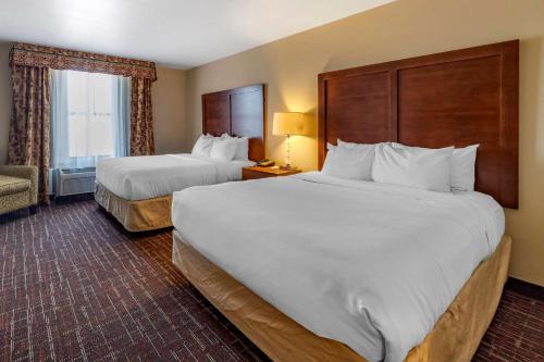 a hotel room with two beds and a chair at Comfort Inn & Suites Shawnee North near I-40 in Shawnee