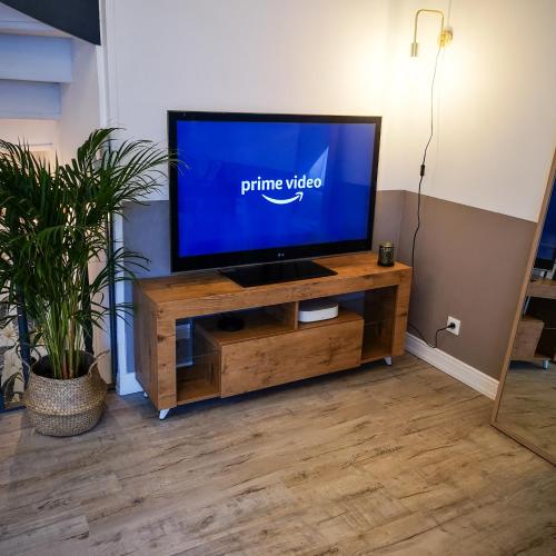 a flat screen tv sitting on a wooden entertainment center at **LA MEZZANINE** Proche Zénith & Centre Ville in Strasbourg