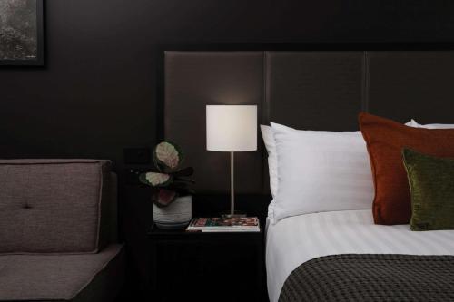 a bedroom with a bed with a lamp on a night stand at Rydges Wellington Airport in Wellington