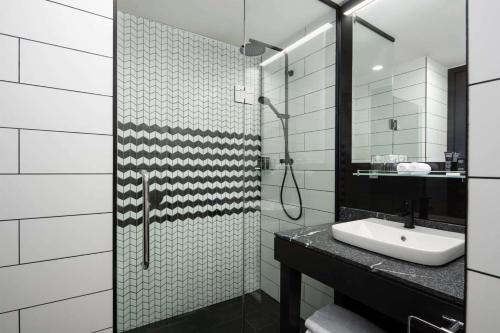 a bathroom with a shower with a sink and a mirror at Rydges Wellington Airport in Wellington