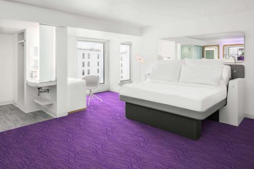 a bedroom with a white bed and a purple carpet at YOTEL Edinburgh in Edinburgh