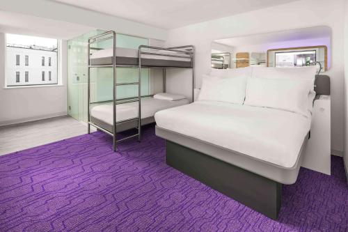 YOTEL Edinburgh في إدنبرة: غرفة نوم مع سرير بطابقين وسجادة أرجوانية