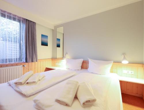 ein Schlafzimmer mit einem weißen Bett mit zwei Handtüchern darauf in der Unterkunft Appartement Riterspöör 24 in Westerland