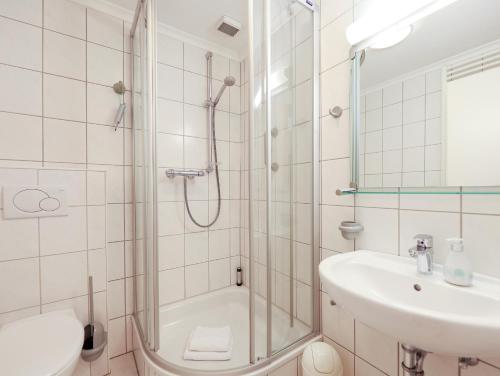 uma casa de banho com um chuveiro, um lavatório e um WC. em Appartement Riterspöör 24 em Westerland