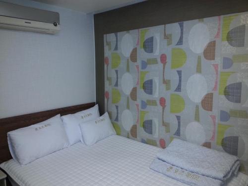 a bed with two white pillows and a wall at Egg Motel in Busan