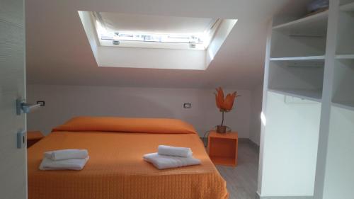 1 dormitorio con 1 cama naranja y 2 toallas en Casa Lorenzo&Luca en Gonnesa