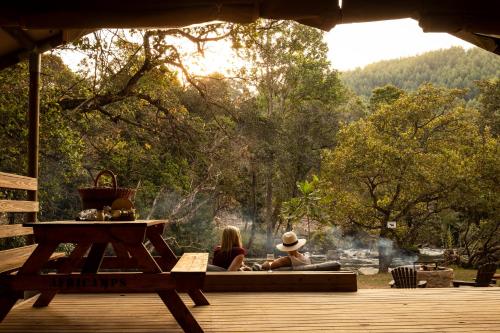two people sitting on a deck looking at the water at AfriCamps at Mackers in Hazyview