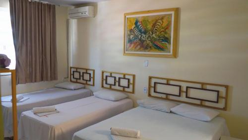 a room with two beds and a painting on the wall at Hotel Itaipu in Goiânia