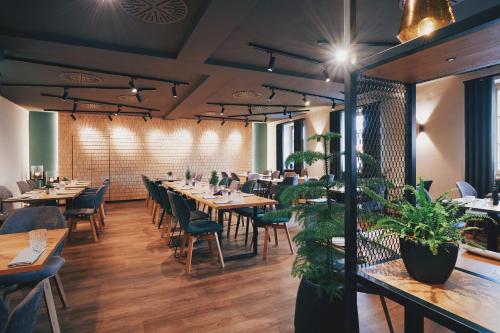 a restaurant with wooden tables and chairs and plants at Hotel Hanauerhof in Appenweier