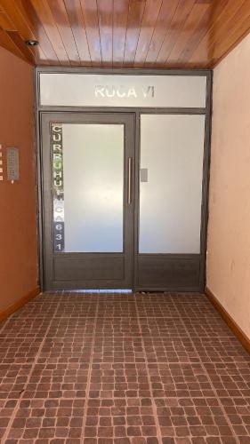 a pair of doors in a room with a brick floor at Departamento Curruhuinca - Deptosxlosandes in San Martín de los Andes