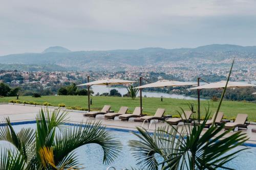 a swimming pool with lounge chairs and umbrellas at Mantis Kivu Marina Bay Hotel in Muhari