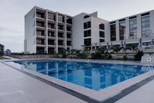 a large swimming pool in front of two buildings at Mantis Kivu Marina Bay Hotel in Muhari