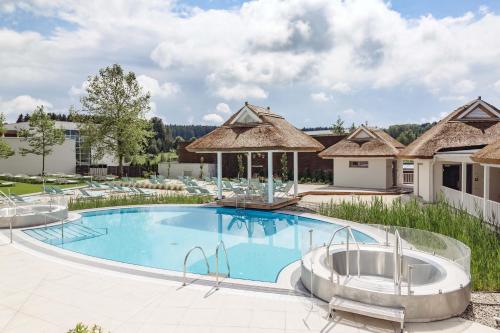 una piscina con due vasche idromassaggio accanto a un edificio di Spa Resort Geinberg a Geinberg