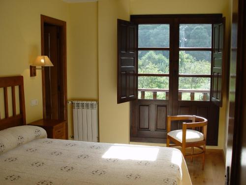 a bedroom with a bed and a window and a chair at Casa Muniellos in Moal