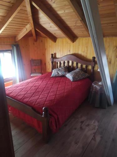 ein Schlafzimmer mit einem großen Bett mit einer roten Bettdecke in der Unterkunft Duplex El Duende in Olavarría