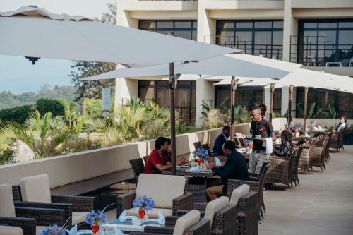a group of people sitting at tables on a patio at Mantis Kivu Marina Bay Hotel in Muhari