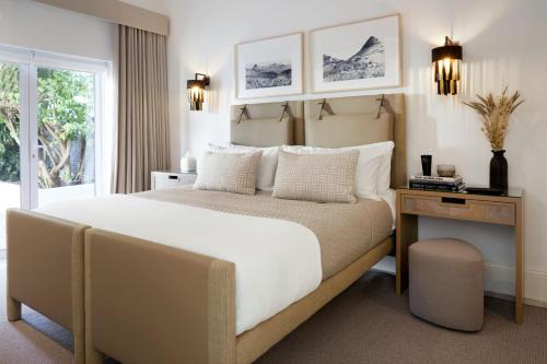 1 dormitorio con 1 cama grande, mesa y ventana en Kaap Mooi Luxury Guest House, en Ciudad del Cabo