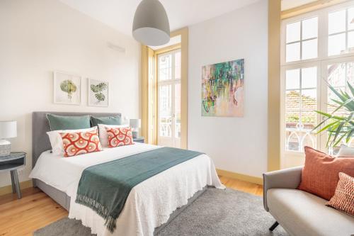 a bedroom with a bed and a couch and windows at São Miguel Apartments in Porto