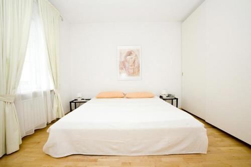 ein weißes Schlafzimmer mit einem weißen Bett und einem Fenster in der Unterkunft Ferienwohnung Bregenz 6 top 3 in Bregenz