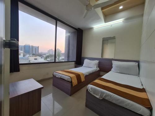 Duas camas num quarto com uma janela grande em Hotel Nova Sun em Ahmedabad