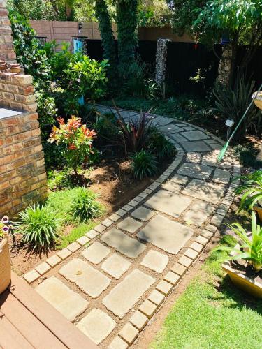a garden with a stone walkway in a yard at Cottonwood Guesthouse Oasis in Bloemfontein