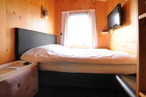 - une petite chambre avec un lit et une télévision dans l'établissement Chalet Egmond, à Egmond aan den Hoef