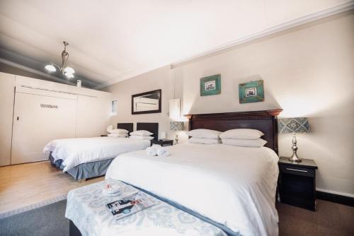 two beds in a room with white sheets at Cottonwood Guesthouse Oasis in Bloemfontein