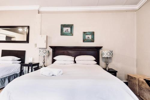 a bedroom with a large white bed with towels on it at Cottonwood Guesthouse Oasis in Bloemfontein