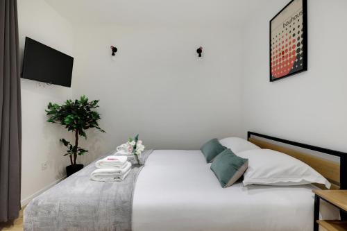 1 cama blanca con almohadas blancas y TV en Parfait studio pour un accès rapide à la Sorbonne! en París