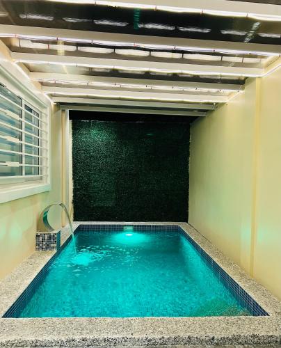 a swimming pool in a room with a green wall at Luxury 3BR Villa w Plunge Pool near SM Batangas City- Instagram-Worthy! in Batangas City