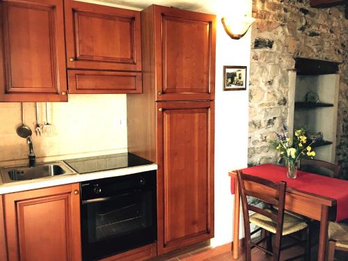 a kitchen with wooden cabinets and a table with a vase of flowers at Agriturismo Montagna Verde Apella in Licciana Nardi