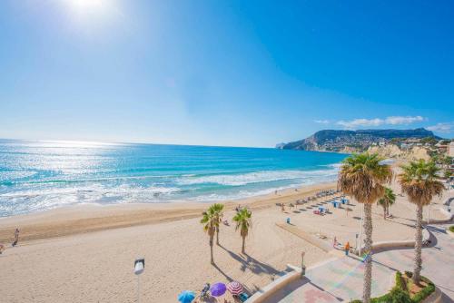 a view of a beach with palm trees and the ocean at Apartamento Capri - PlusHolidays in Calpe