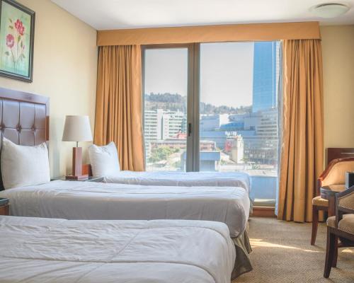 um quarto de hotel com duas camas e uma grande janela em Hotel Stanford em Santiago