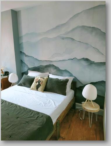 a bedroom with a bed with a mountain mural on the wall at La Belle D'Âme - Guest House in Prades