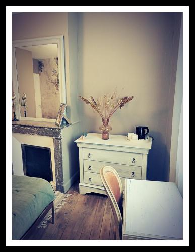 a bedroom with a dresser and a mirror and a table at La Belle D'Âme - Guest House in Prades