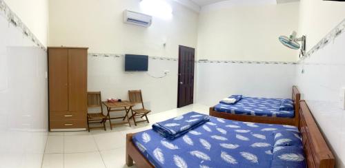 a room with two beds and a desk in it at Nhà Nghĩ Hải Yến in Long Hai