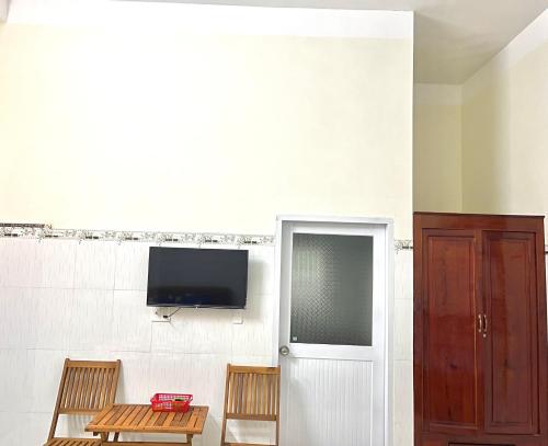 a room with two chairs and a tv on a wall at Nhà Nghĩ Hải Yến in Long Hai