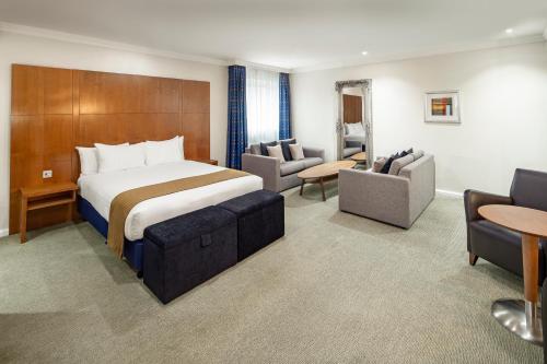 ベージングストークにあるホリデイ イン ベージングストークのベッドとリビングルームが備わるホテルルームです。