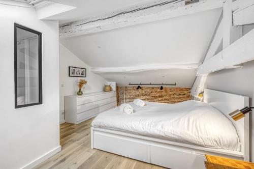 une chambre avec un lit blanc et un mur de briques dans l'établissement LE BROADWAY - Duplex entièrement rénové, à Toulouse