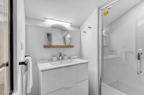 une salle de bain blanche avec un lavabo et un miroir dans l'établissement LE BROADWAY - Duplex entièrement rénové, à Toulouse